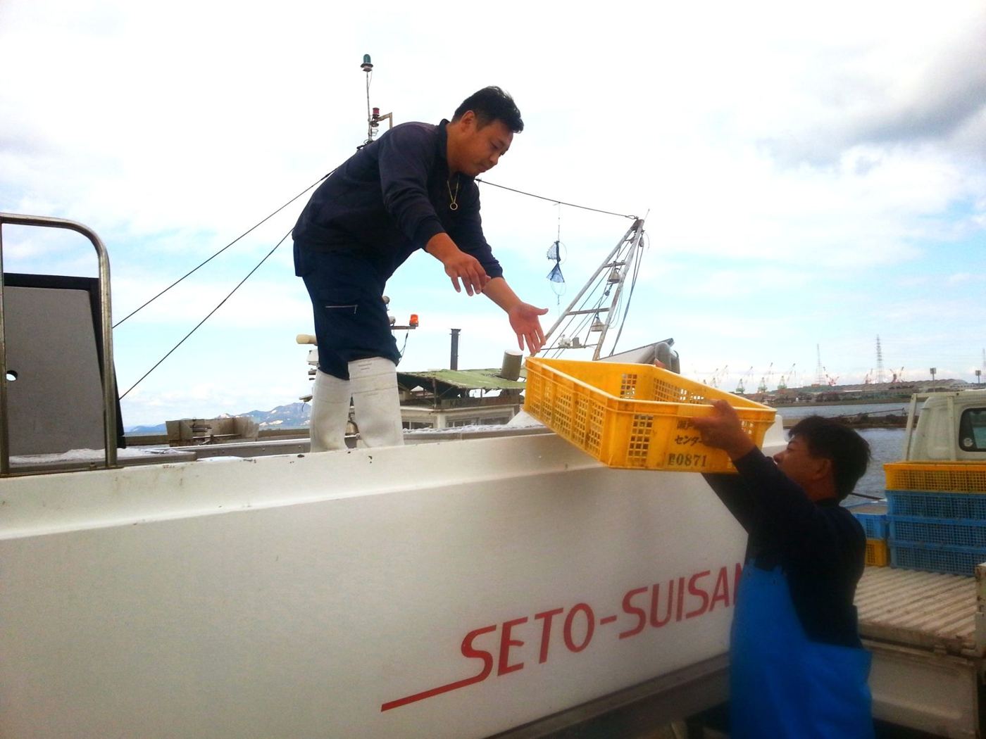 漁船から活魚のかごを受け取る社員